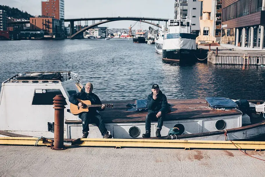 hommes-assis-en-jouant-de-la-guitare-sur-un-bateau-a-quai-pendant-la-journee
